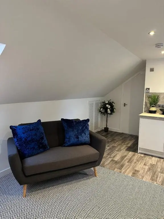 a couch with blue pillows in a living room at An Cuiltheann Apartment in Turriff