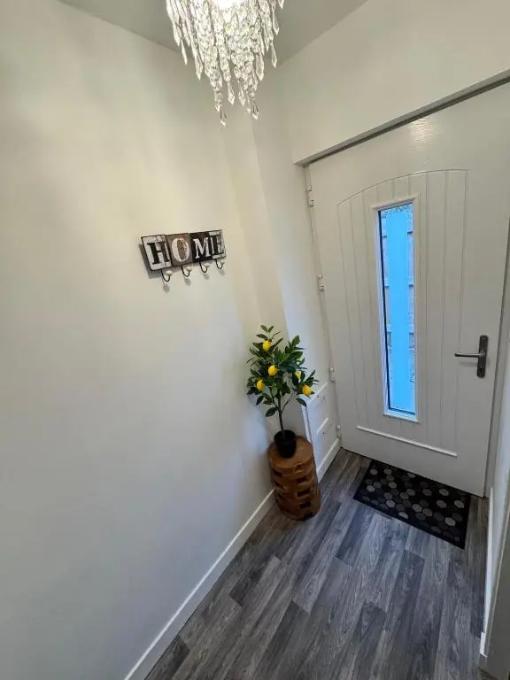 a hallway with a white door and a potted plant at An Cuiltheann Apartment in Turriff
