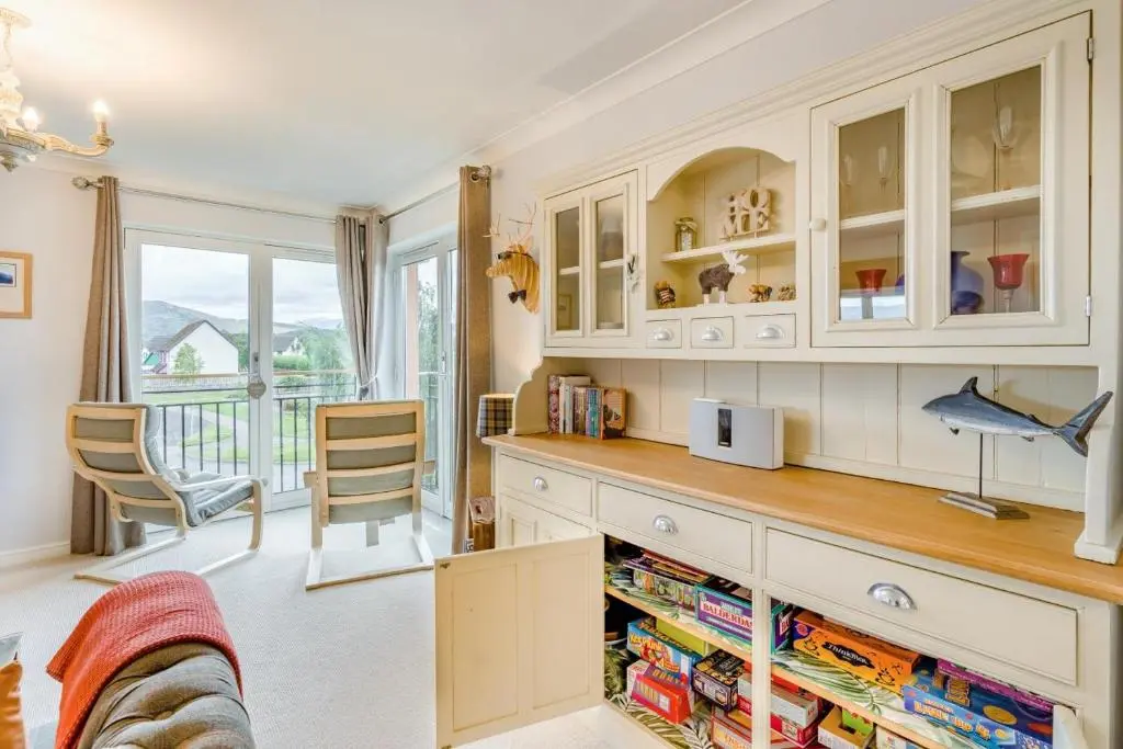 a kitchen with white cabinets and a table with books at 2 Bed in Aviemore oc-t30584 in Aviemore