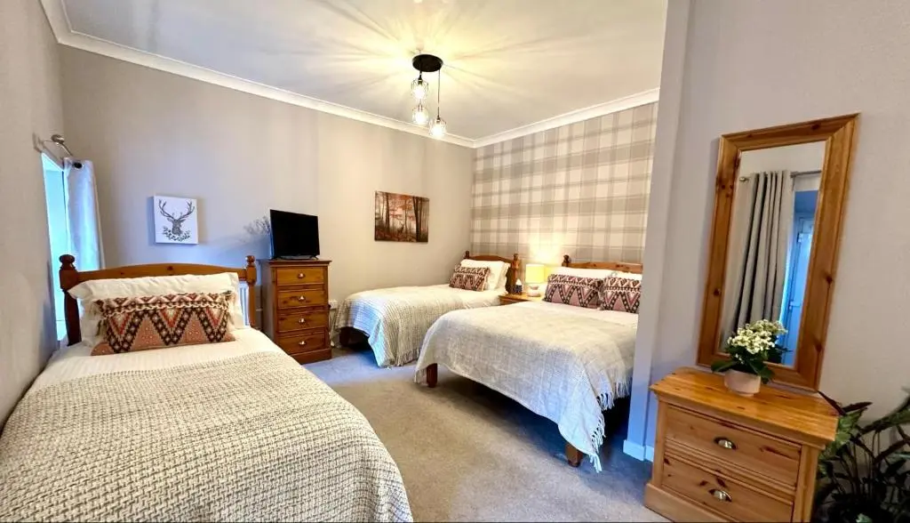 a bedroom with two beds and a mirror at Beechtree Cottage, Ardle Family Room, Kirkmichael in Kirkmichael