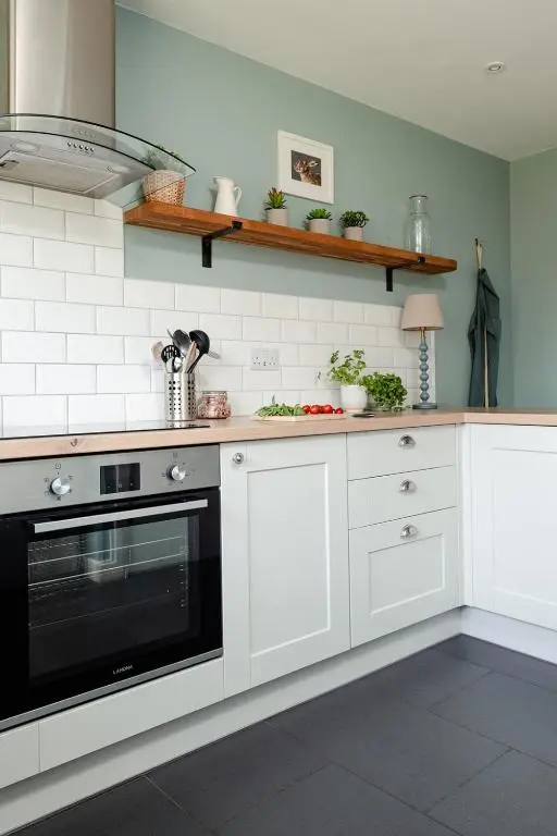 a kitchen with white cabinets and a black oven at Park Cottage - Seasgair Lodges in Kingussie