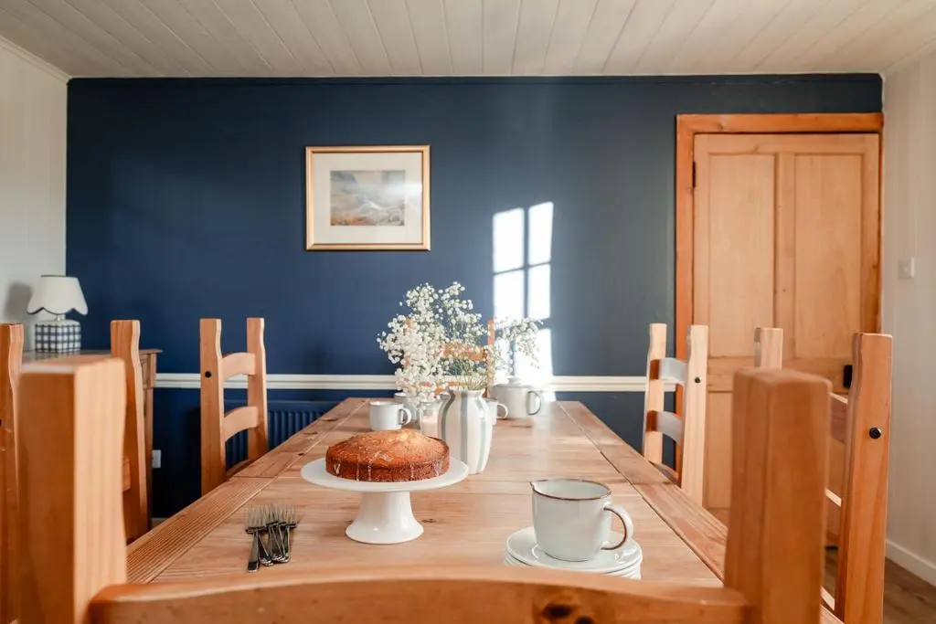 a dining room with a table and a blue wall at Park Cottage - Seasgair Lodges in Kingussie