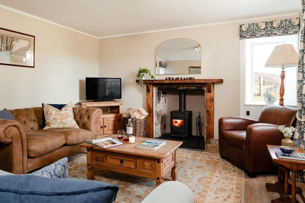 a living room with leather furniture and a fireplace at Park Cottage - Seasgair Lodges in Kingussie