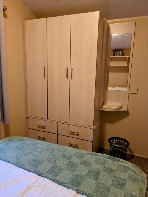 a bedroom with a bed and a cupboard at Aurora on the Dunes- Cozy Coastal Retreat with Scenic Views in Lossiemouth