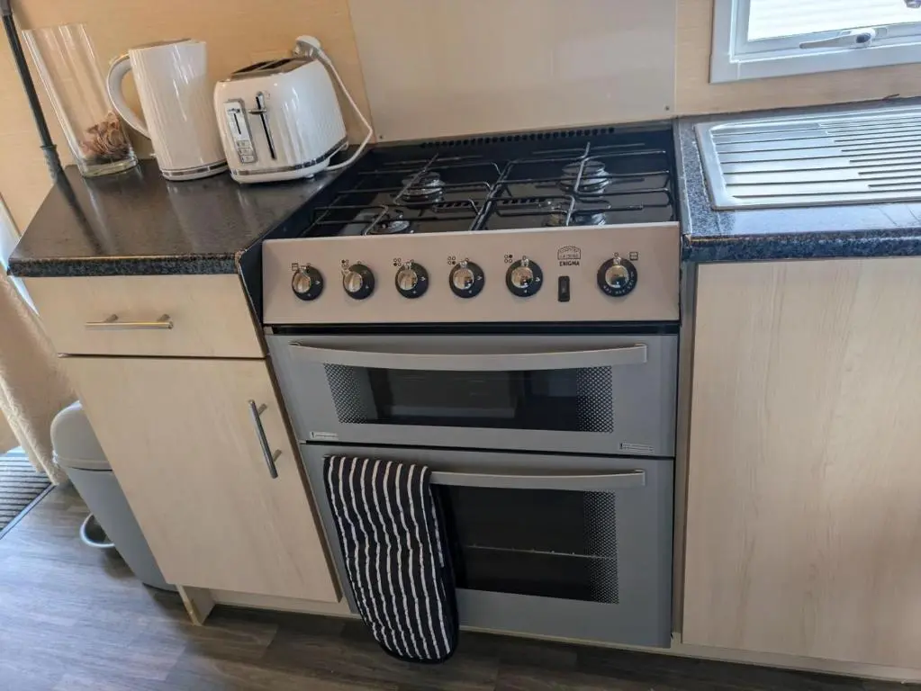 a kitchen with a stove top oven in a kitchen at Aurora on the Dunes- Cozy Coastal Retreat with Scenic Views in Lossiemouth