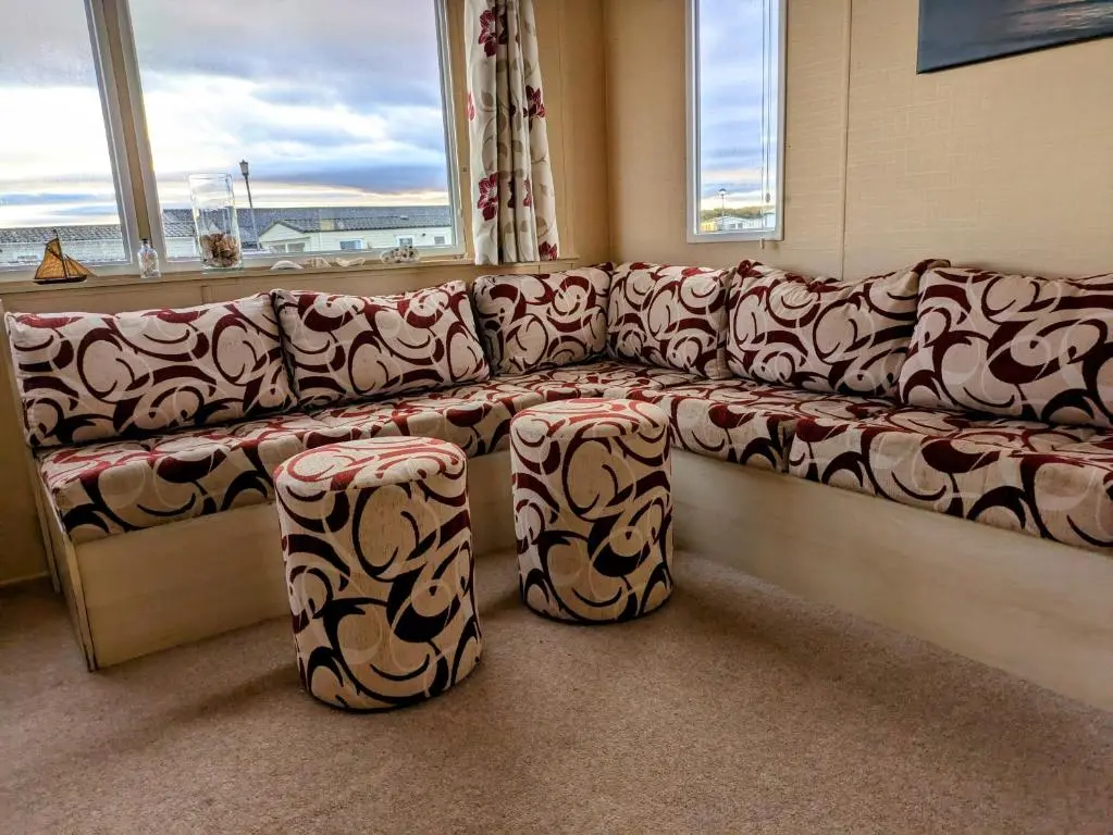 a couch sitting in a room with a window at Aurora on the Dunes- Cozy Coastal Retreat with Scenic Views in Lossiemouth