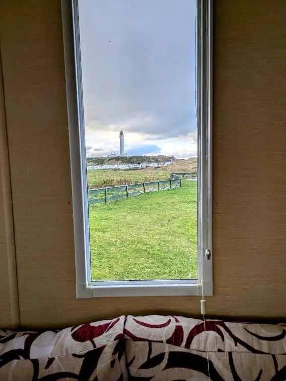 a window in a room with a view of a field at Aurora on the Dunes- Cozy Coastal Retreat with Scenic Views in Lossiemouth