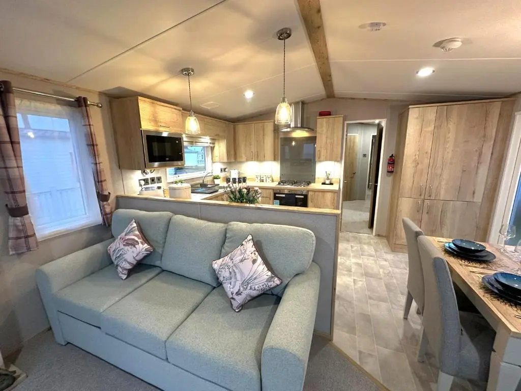 a living room with a couch and a kitchen at Clearwater View - Stunning sea views from large deck in Burghead