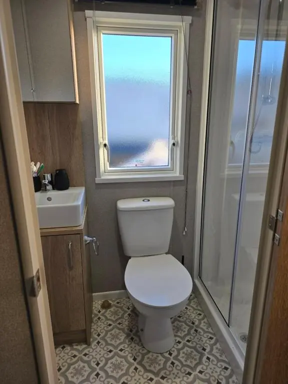 a bathroom with a toilet and a sink and a window at Clearwater View - Stunning sea views from large deck in Burghead