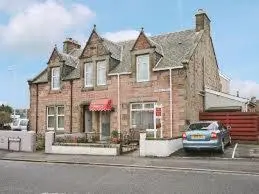 a large brick house with a car parked in front of it at Ardgarry Holiday House in Inverness