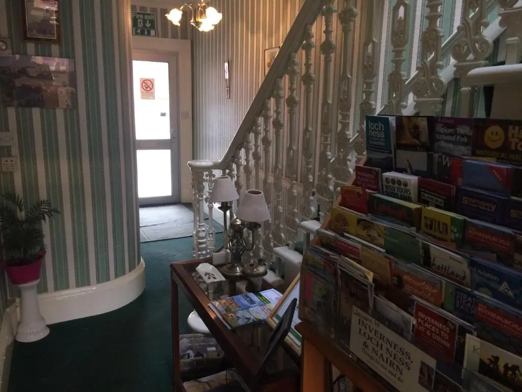 a room with a staircase with books on the wall at Ardgarry Holiday House in Inverness