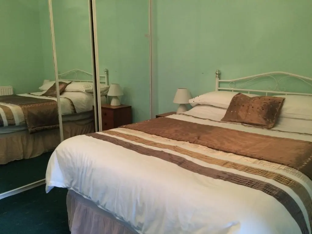 a bedroom with a bed and a large mirror at Ardgarry Holiday House in Inverness