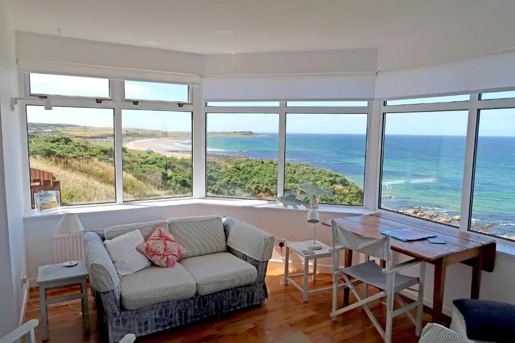 a living room with a couch and a table at Bright comfy home, sea views and big skies in Banff