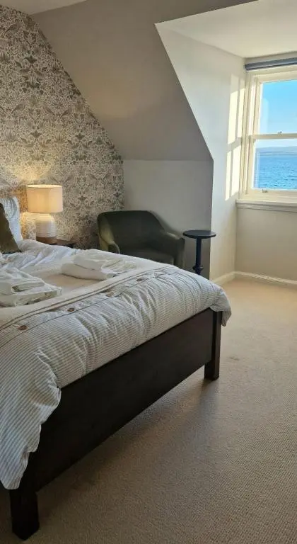 a bedroom with a bed with a chair and a window at North Coast Property - Avoch Beach House - Luxury house with sea views in Avoch