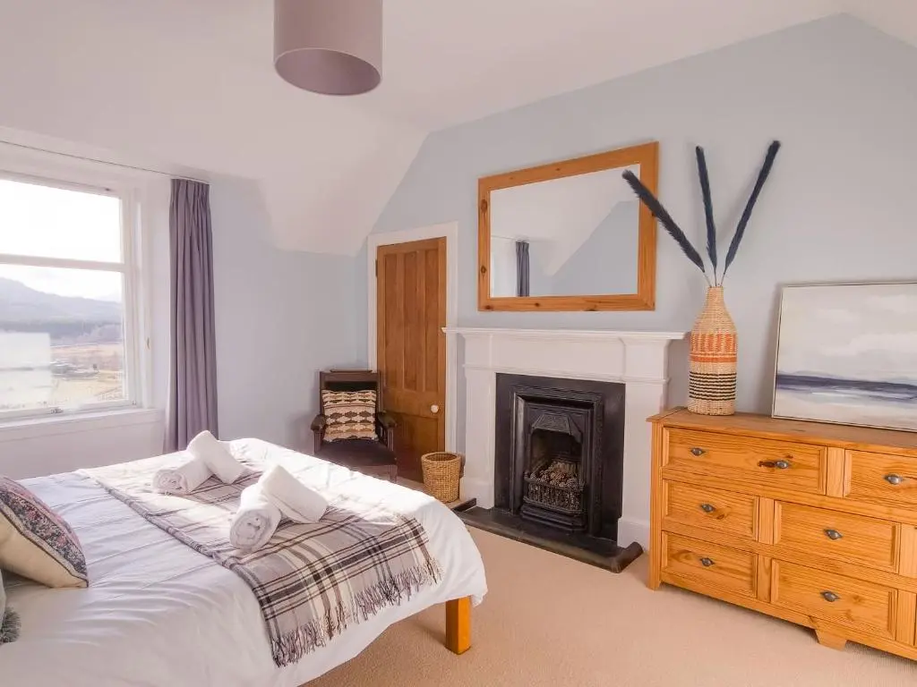 a bedroom with a bed with a fireplace and a mirror at Schoolhouse in Laggan