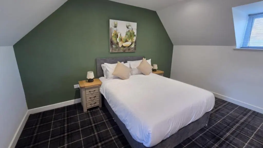 a bedroom with a white bed and a green wall at Woodside House in Crook of Alves