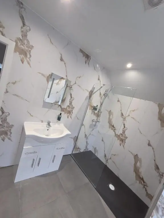 a bathroom with a sink and a marble wall at Woodside House in Crook of Alves