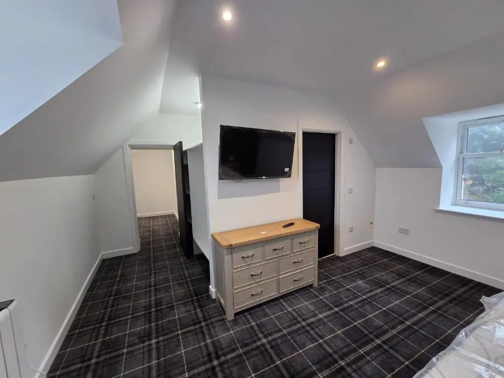 a bedroom with a tv on the wall and a dresser at Woodside House in Crook of Alves