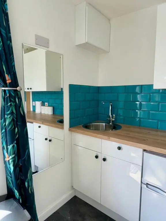 a small kitchen with a sink and blue tiles at Brae Cabin in Inverness