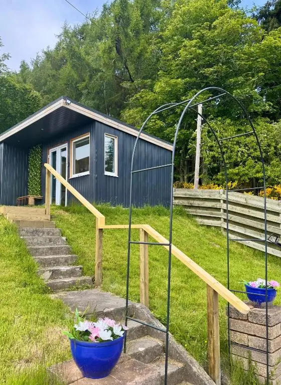 a tiny house with two blue flower pots on the steps at Brae Cabin in Inverness