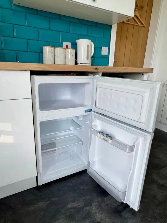 an empty refrigerator with its door open in a kitchen at Brae Cabin in Inverness
