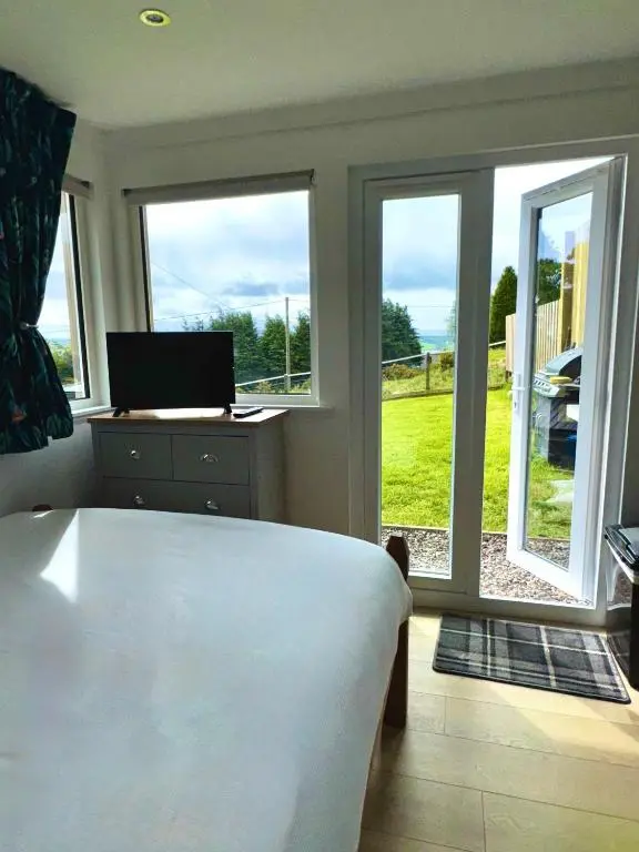 a bedroom with a bed and a window with a view at Brae Cabin in Inverness