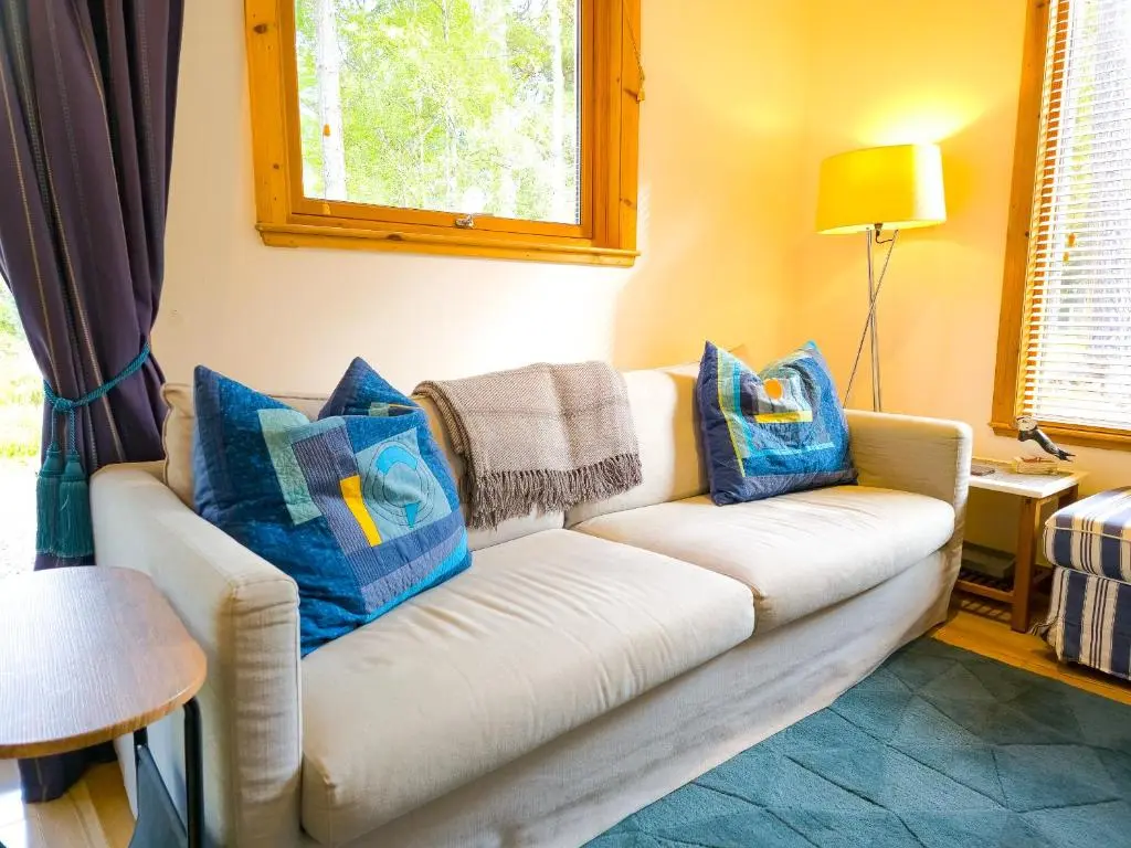 a living room with a white couch with blue pillows at Taigh Mathair Taigh Mathair in Nethy Bridge