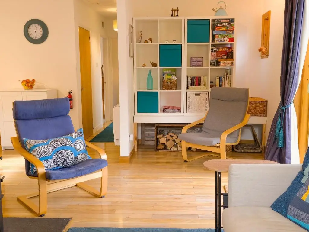 a living room with two chairs and a fireplace at Taigh Mathair Taigh Mathair in Nethy Bridge