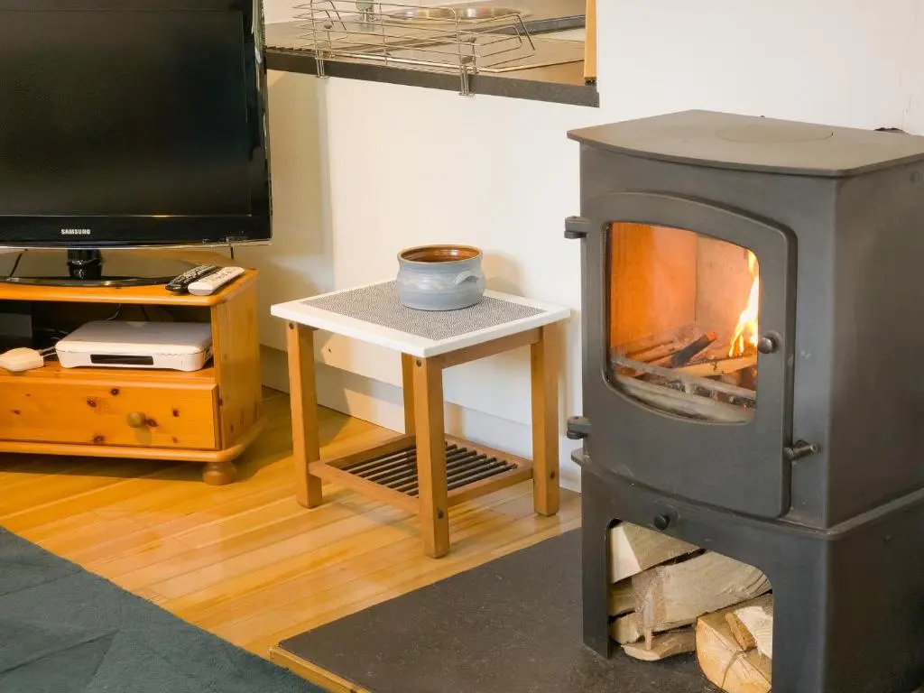 a living room with a fireplace and a tv at Taigh Mathair Taigh Mathair in Nethy Bridge