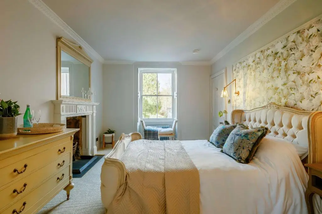a bedroom with a bed and a dresser and a fireplace at Burnhervie House in Inverurie
