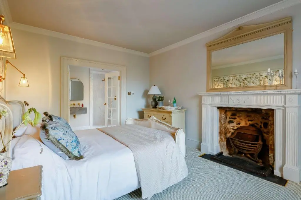 a bedroom with a white bed and a fireplace at Burnhervie House in Inverurie