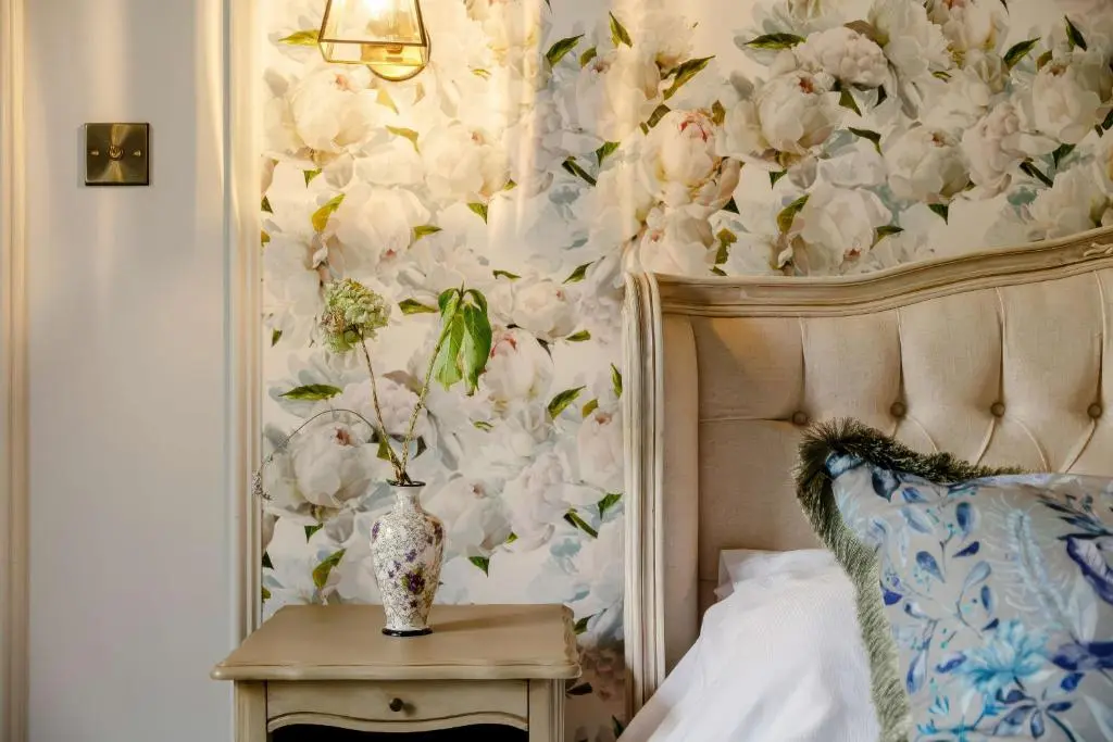 a bedroom with a flower wall with a vase on a table at Burnhervie House in Inverurie