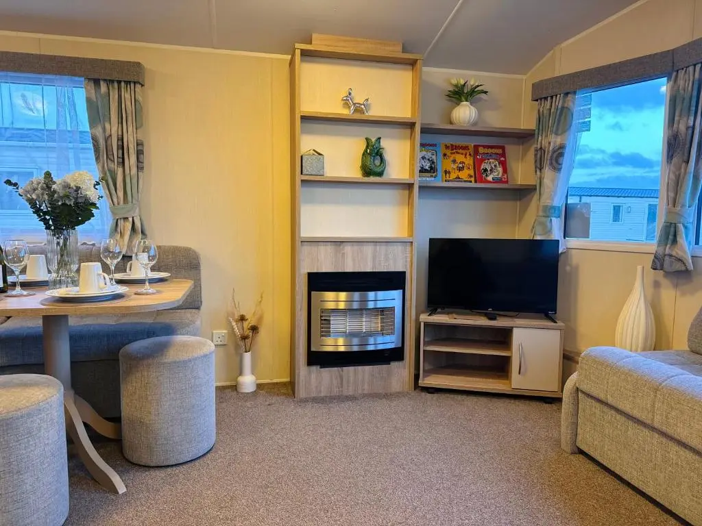 a living room with a tv and a fireplace at Little Cha-Am Caravan Hire at Silver Sands in Lossiemouth