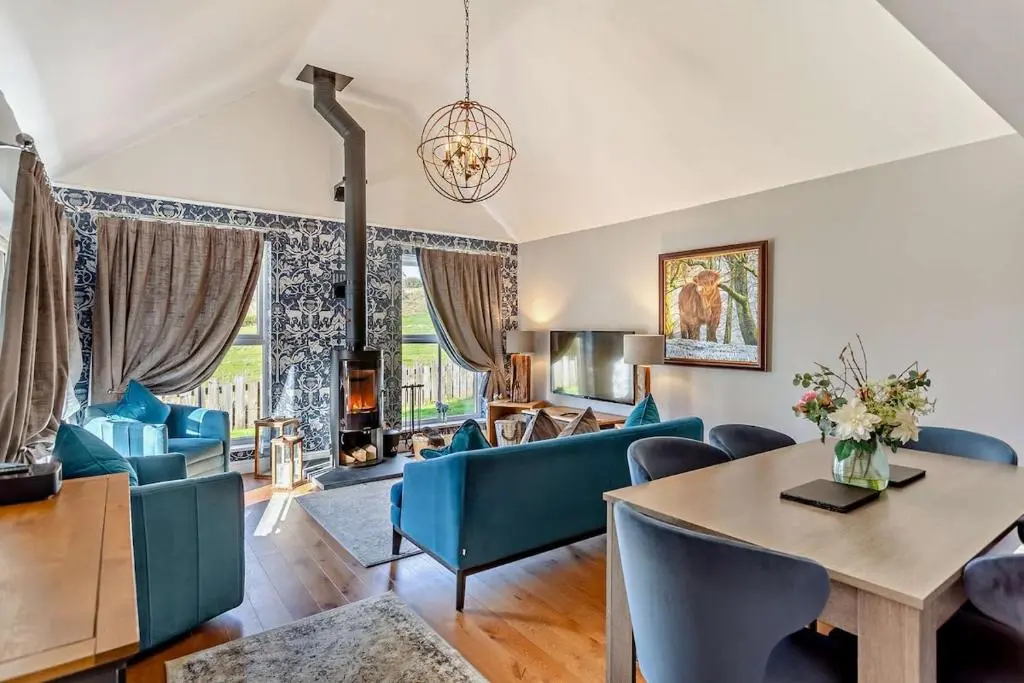 a living room with a table and blue chairs at Glenmore Lodge in Skye of Curr
