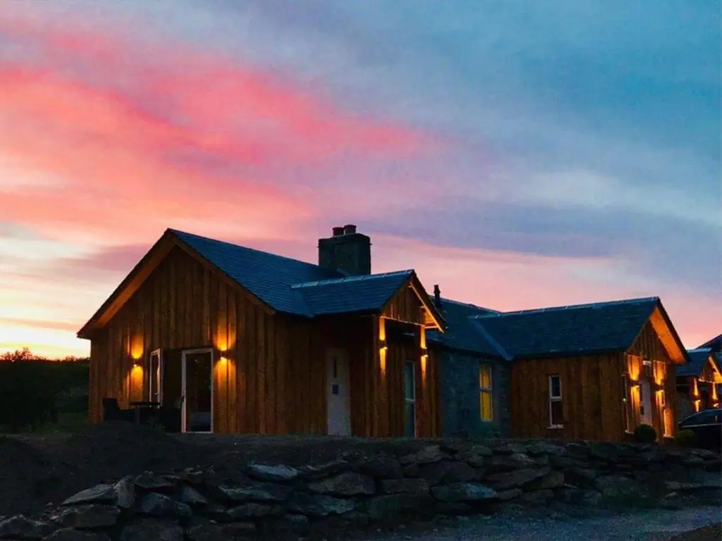 a wooden house with a sunset in the background at Glenmore Lodge in Skye of Curr