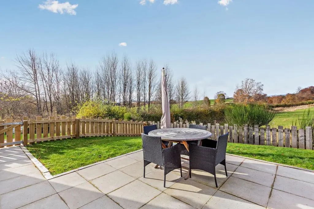 a patio with a table and chairs and a fence at Glenmore Lodge in Skye of Curr