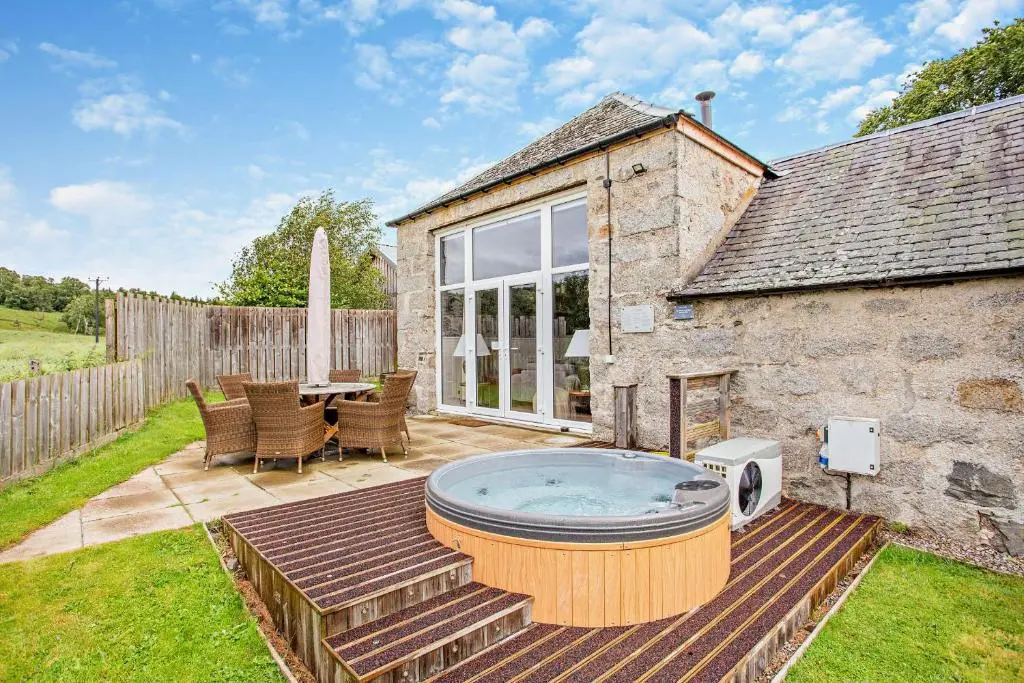 a patio with a hot tub in the backyard of a house at Cairngorm Cottage in Skye of Curr