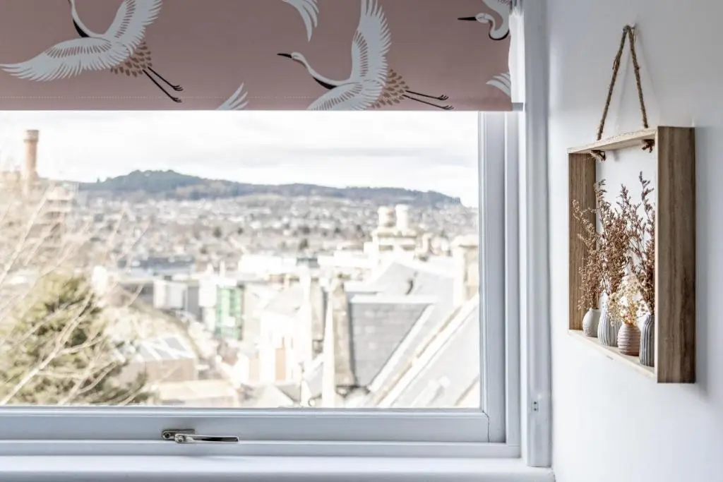 a window with two birds flying over a city at Ness Heights, Spacious City Centre Townhouse in Inverness