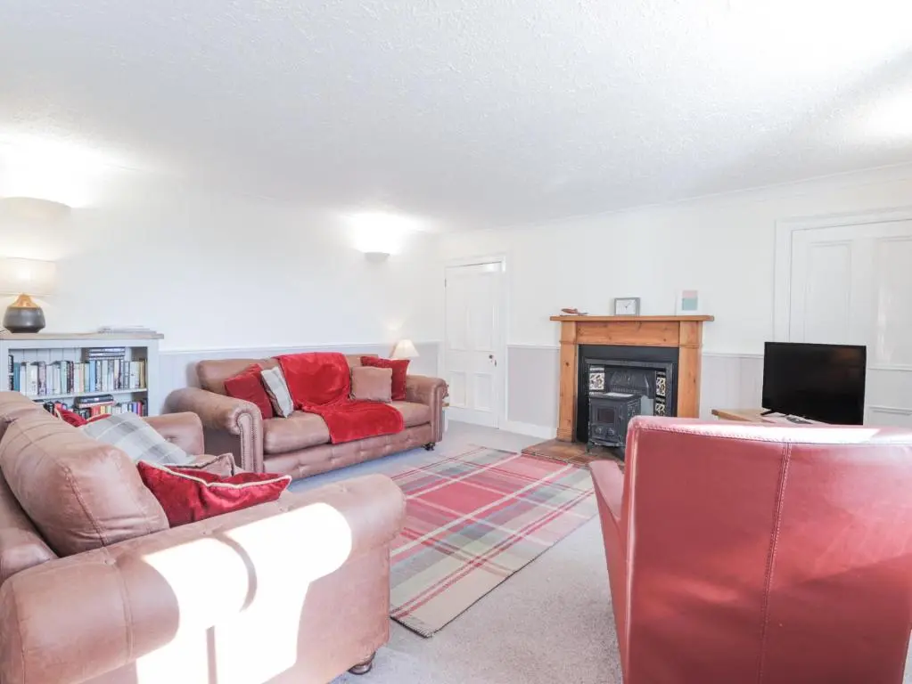 a living room with two couches and a fireplace at Fuchsia Cottage in Fortrose