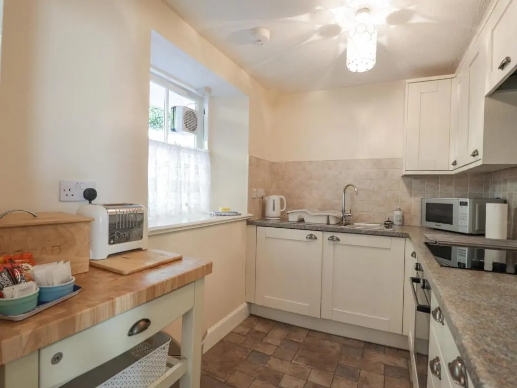 a kitchen with white cabinets and a counter top at Fuchsia Cottage in Fortrose