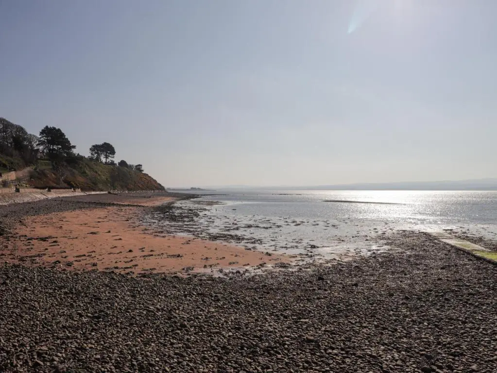 a beach with a rocky shoreline next to the ocean at Fuchsia Cottage in Fortrose