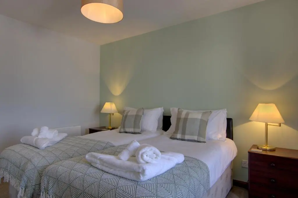a bedroom with two beds with white towels on them at 2 Links View, Brora in Brora