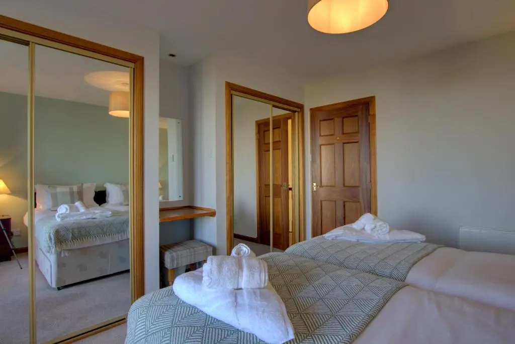 a bedroom with two beds and a mirror at 2 Links View, Brora in Brora