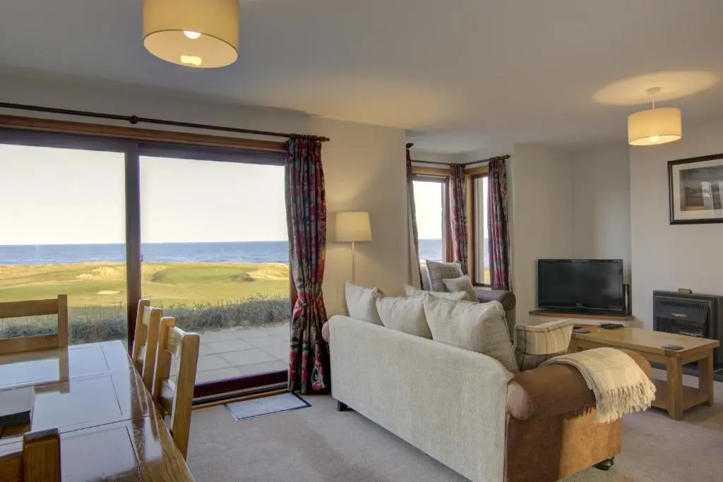a living room with a couch and a large window at 2 Links View, Brora in Brora