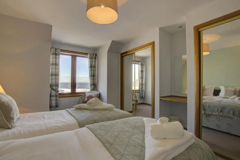 a bedroom with two beds and a mirror at 2 Links View, Brora in Brora