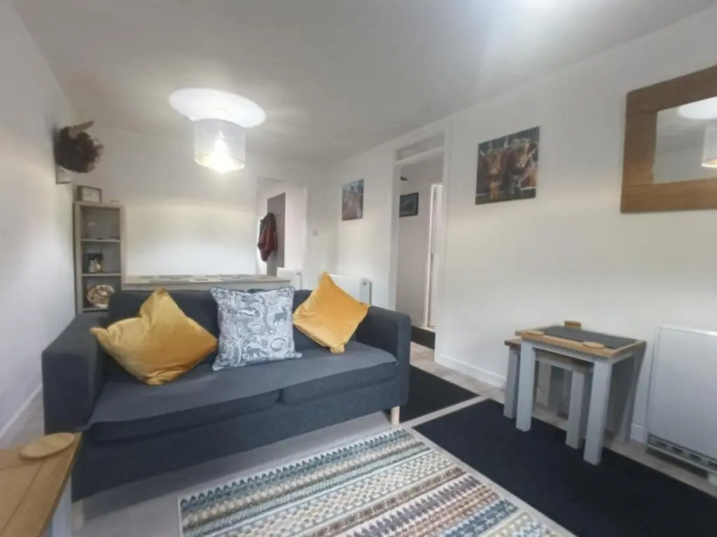 a living room with a blue couch and a table at Steam Train Cottage in Aviemore