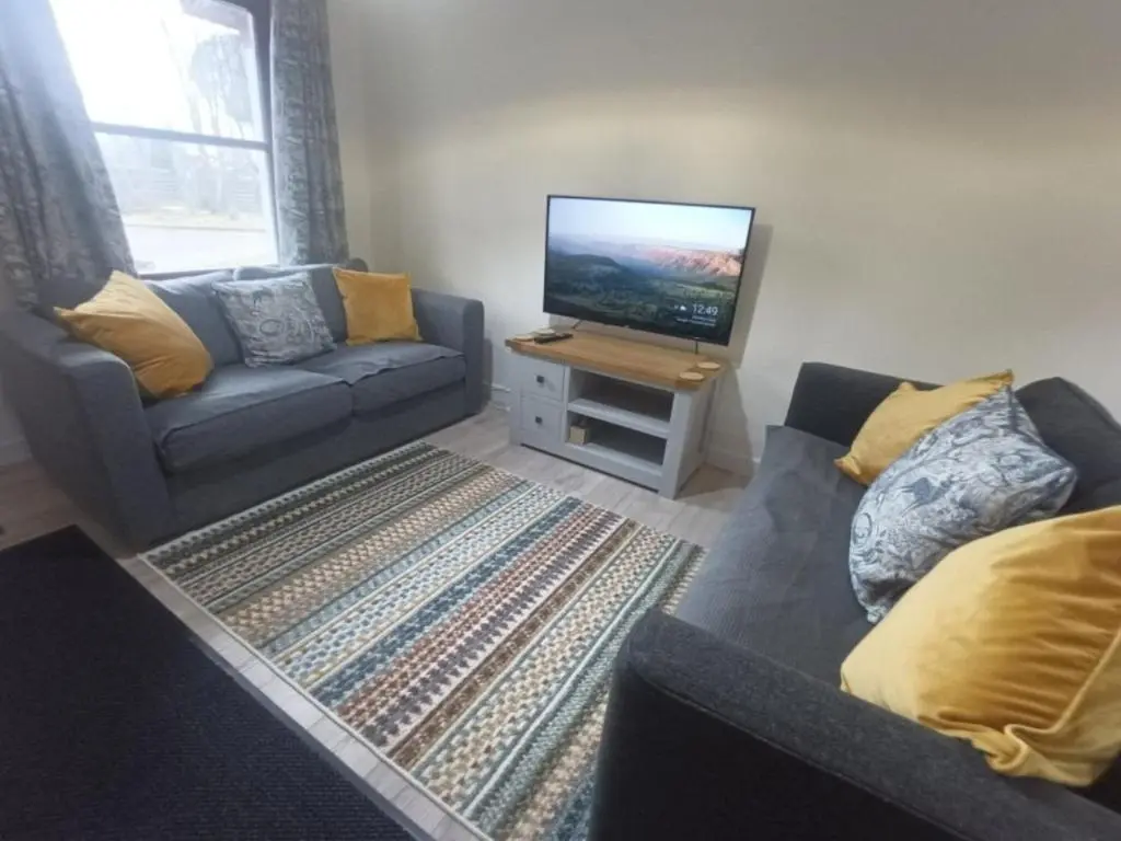 a living room with a couch and a flat screen tv at Steam Train Cottage in Aviemore