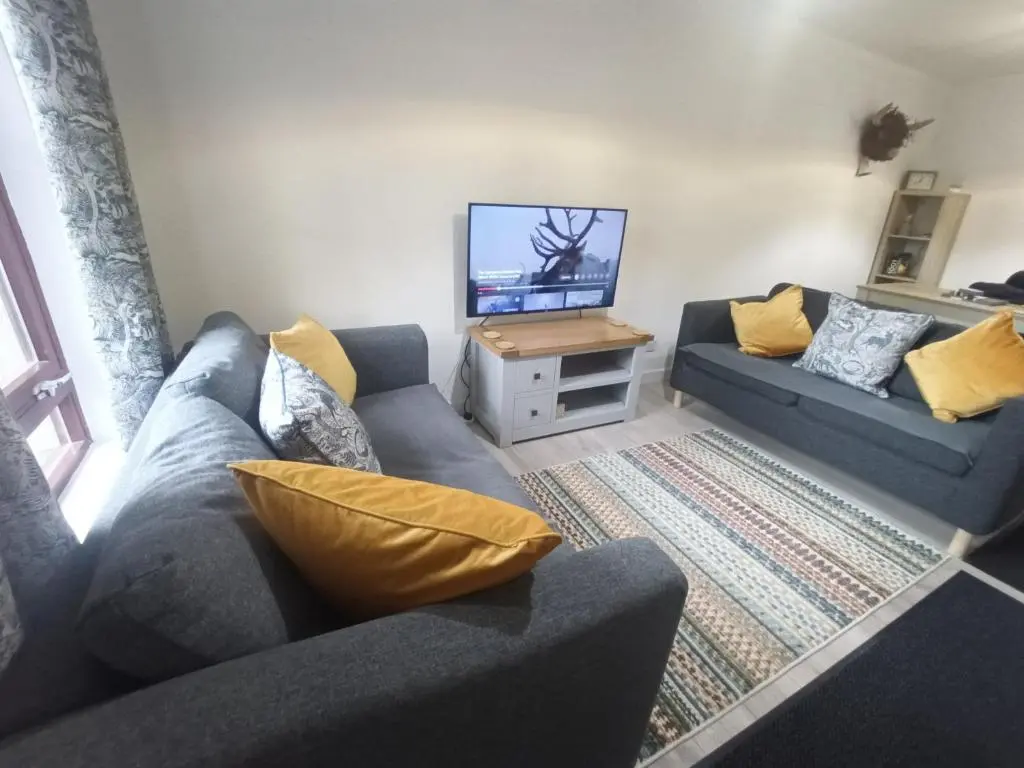 a living room with two couches and a flat screen tv at Steam Train Cottage in Aviemore