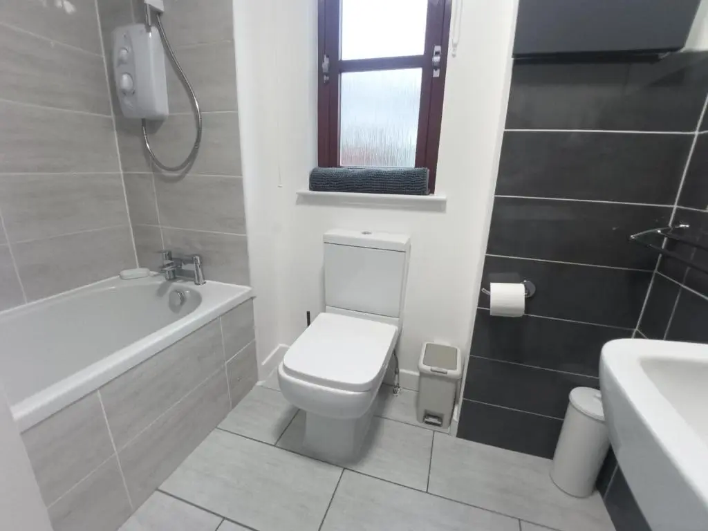 a bathroom with a toilet and a tub and a sink at Steam Train Cottage in Aviemore