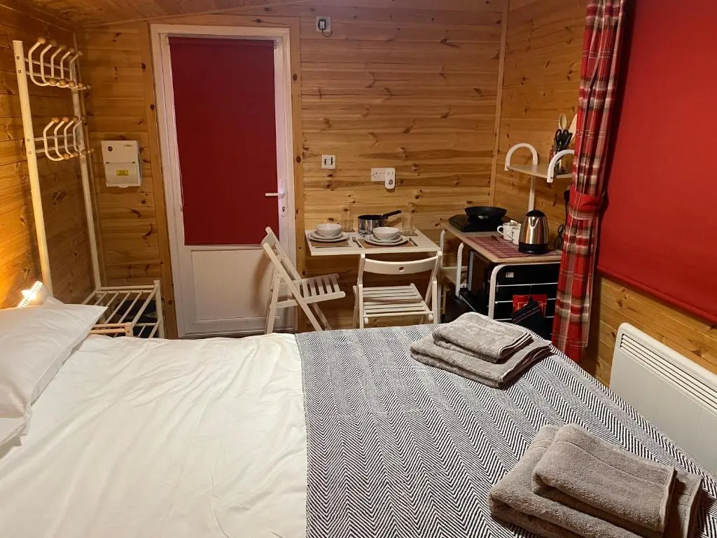 a bedroom with a bed and a table in a room at An Cabar - Cabin in Aviemore, Cairngorms NP in Aviemore